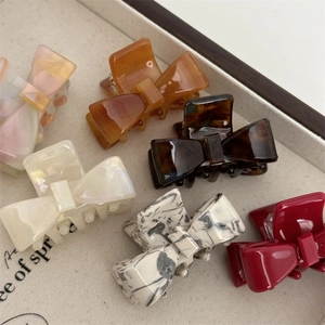 Detail view of colorful bow-shaped hair claws in acetate material on a tray