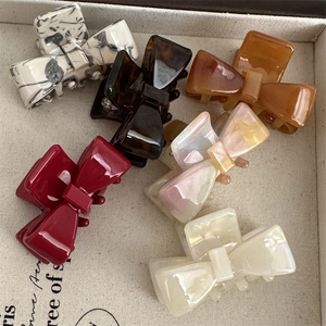 Elegant cellulose acetate bow hair claws in marble and tortoiseshell patterns in a tray