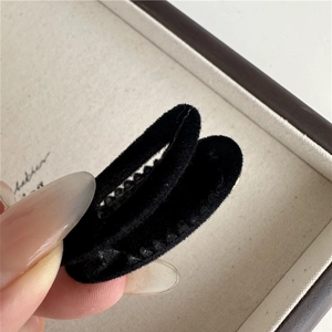 Detail view of the black flocked velvet texture on the teardrop-shaped metal hair clip