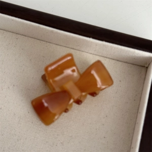 Macro detail of amber acetate bow hair claw clip showing textured marble pattern