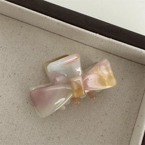 Macro view of a sweet bow hair claw clip with a pink and yellow gradient acetate finish