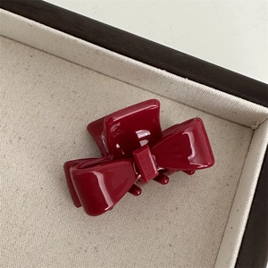 Detailed view of dark red acetate bow hair claw clip showing polished texture and teeth
