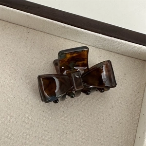 Macro shot of tortoiseshell acetate bow hair claw with glossy amber resin texture