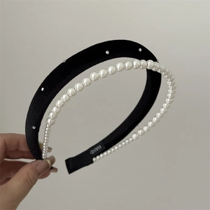 Detailed close-up of double-layer headband with white faux pearls and black fabric base