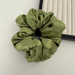 Gros plan du chouchou en satin vert olive montrant la texture soyeuse et les plis