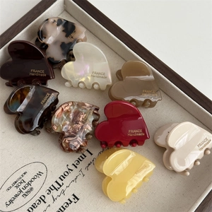 Acetate heart-shaped hair claw clips in various colors arranged in a wooden tray
