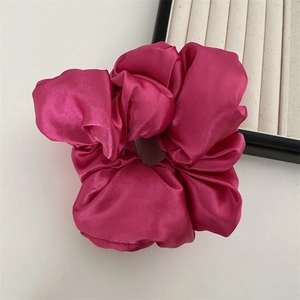 Gros plan d'un chouchou en satin rose rouge vif avec une texture de soie lisse près d'une boîte