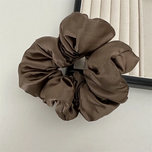 Gros plan sur un chouchou en satin marron avec texture soyeuse et plis élégants