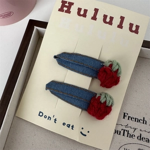 Gros plan de barrettes en denim vintage avec fraises tricotées à la main et carte