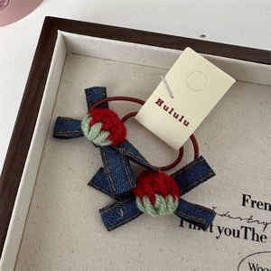 Détail de chouchous fraises en crochet vintage avec nœud en jean sur plateau