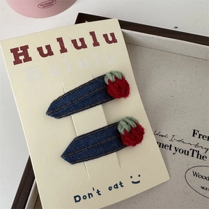 Détail de pinces à cheveux fraise au crochet faites main sur tissu denim bleu