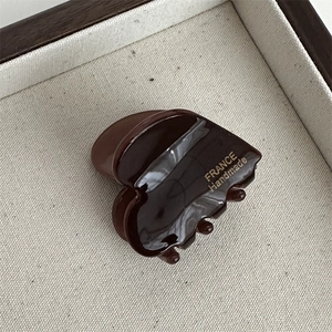 Detailed macro view of small dark brown heart claw clip with golden France Handmade text