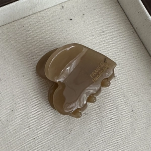 Detail of a brown acetate heart hair claw with golden France Handmade logo lettering