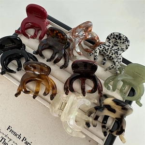 French style acetate hair claw clips in various colors shown from a top view on a display tray