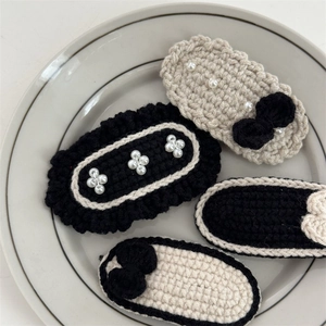 Handmade crochet hair clips with pearls in black and cream white on a ceramic tray