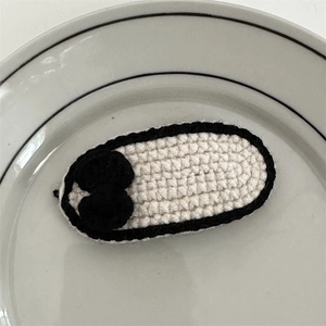 Close-up of handmade crochet hair clip with black bow detail on white knitted oval base