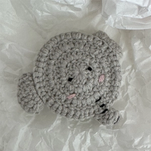 Détail d'une pince à cheveux en crochet gris fait main sur fond blanc texturé