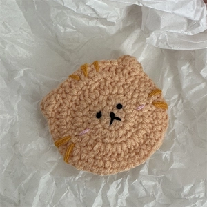 Vue détaillée d'une pince à cheveux chat en crochet orange faite main sur fond de papier