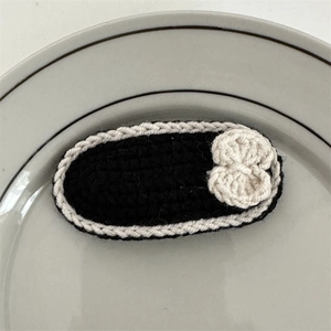 Close-up of handmade black and white crochet hair clip with a small white bow detail