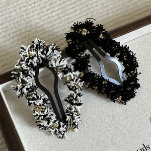 Close-up of elegant tweed hair clips with metallic gold threads and BB snap design