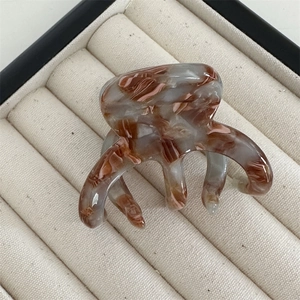 Close-up of brown marble texture hair claw with multi-tooth design in a display box