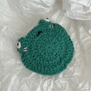 Détail d'une pince à cheveux grenouille en laine tricotée main avec texture douce et visage