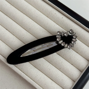 Detail of black velvet BB hair clip featuring a sparkling rhinestone heart on display