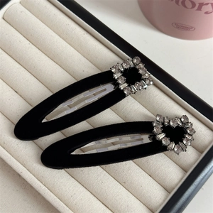 Pair of black velvet hair clips with rhinestone heart and square charms on jewelry tray