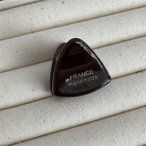 Gros plan sur la pince à cheveux en acétate marron foncé avec logo doré fait main