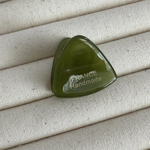 Détail macro d'une pince à cheveux en acétate vert avec logo doré fait à la main