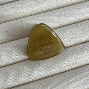 Gros plan d'une pince à cheveux triangle en acétate vert olive avec gravure fait main
