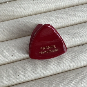 Détail de mini pince à cheveux triangle bordeaux en acétate avec logo doré fait main