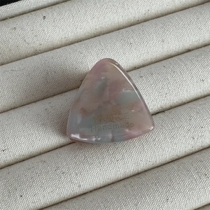 Vue macro d'une pince à cheveux triangle marbré rose et gris avec lettrage fait main