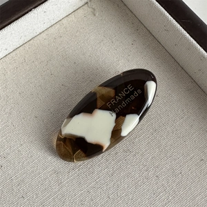 Close-up of oval tortoiseshell hair clip with gold France Handmade engraved text