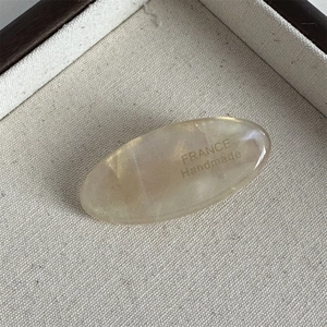 Detail view of oval champagne acetate hair clip with FRANCE Handmade engraving