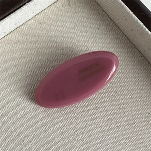 Close-up of pink oval acetate hair clip with FRANCE Handmade engraving on fabric tray