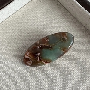 Macro detail of oval acetate hair clip featuring vintage marble texture and France engraving