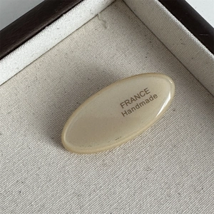 Detailed close-up of acetate oval hair clip with gold France Handmade lettering
