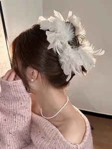 Close-up of fluffy white ostrich feather hair claw clip worn by model with pearl jewelry