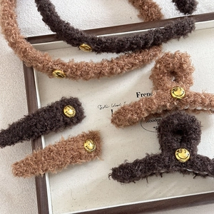 Braunes Teddy-Plüsch-Haarschmuck-Set mit goldenem Smiley auf einem Holztablett