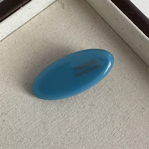 Close-up of a blue oval acetate hair clip featuring a France Handmade engraved logo