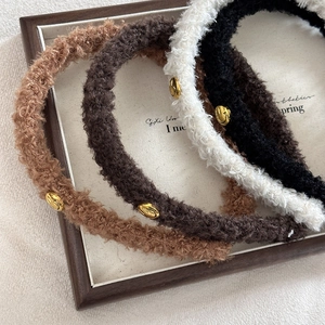 Detailansicht von Plüsch-Haarbändern aus Lammwolle mit goldenem Smiley-Emblem und weicher Textur