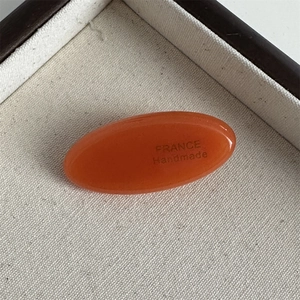 Detailed close-up of handmade amber oval acetate hair clip with France engraving