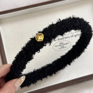 Nahaufnahme der schwarzen Teddy-Plüsch-Haarklammer mit goldenem Smiley-Detail