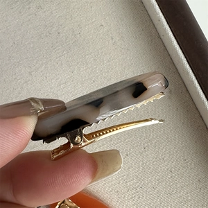 Close-up of golden metal alligator clip with marbled black and white acetate finish