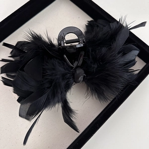Detailed close-up of a large black hair claw clip with elegant ostrich feather decoration