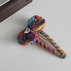 Vue détaillée de la pince à cheveux en laine arc-en-ciel crochetée avec bouton argenté