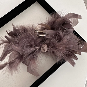 Close-up of fluffy ostrich feathers on a premium dusty rose hair claw clip