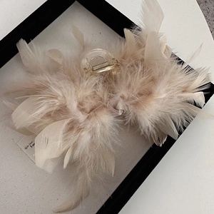 Detail showing elegant beige ostrich feathers on a large acrylic hair claw clip for women