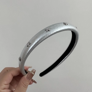 Detailed view of a silver headband featuring sparkling rhinestone stars and a black lining